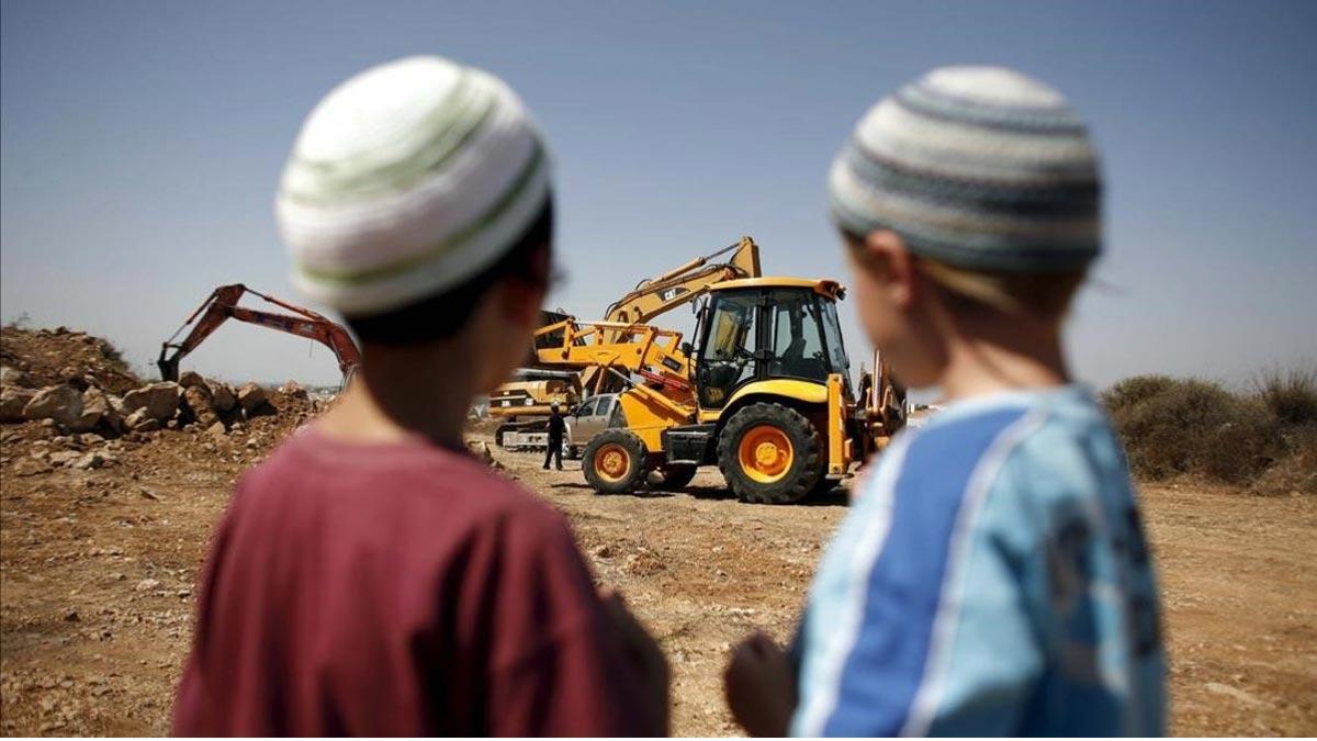 Estados Unidos deja de considerar ilegales los asentamientos israelís en Cisjordania. En la foto, dos niños judíos observan una retroexcavadora utilizada en la construcción de unas 50 viviendas en el asentamiento judío de Ariel.