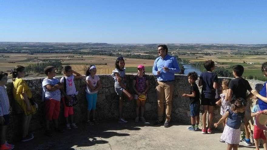 El alcalde explica a los niños participantes en el recorrido la historia del Alcázar y el puente.