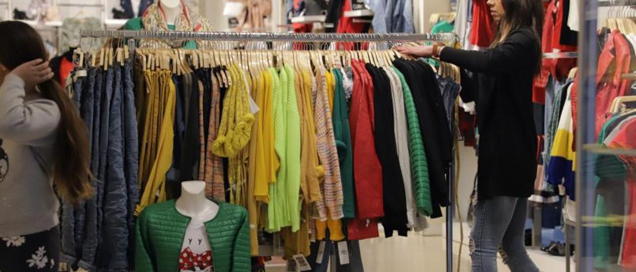 Una mujer ordena una percha en una tienda de ropa del centro de Gandia. | XIMO FERRI