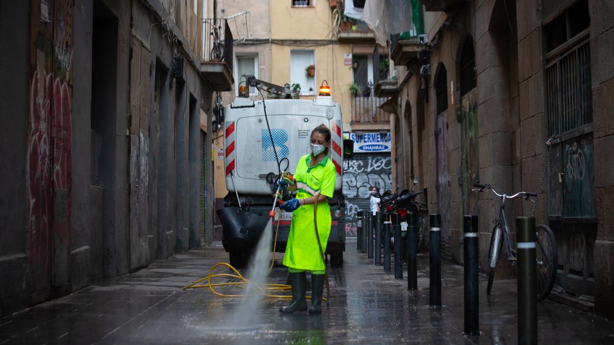 Una trabajadora limpia una vía de Barcelona.