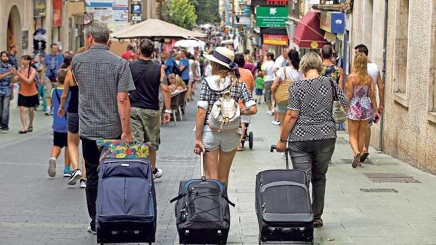 Tres turistas caminan por las calles de Palma con las maletas del equipaje.