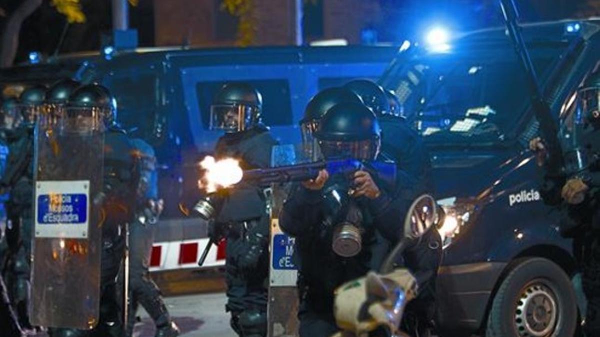 Un agente de los antidisturbios de los Mossos dispara una escopeta apta tanto para salvas como para bolas de goma, el 14-N en Barcelona.