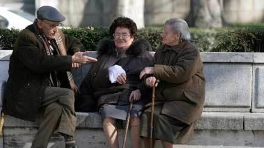Tres personas mayores conversan en un parque.