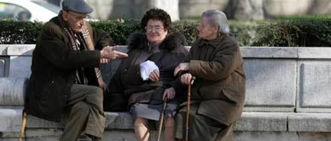 Tres personas mayores conversan en un parque.