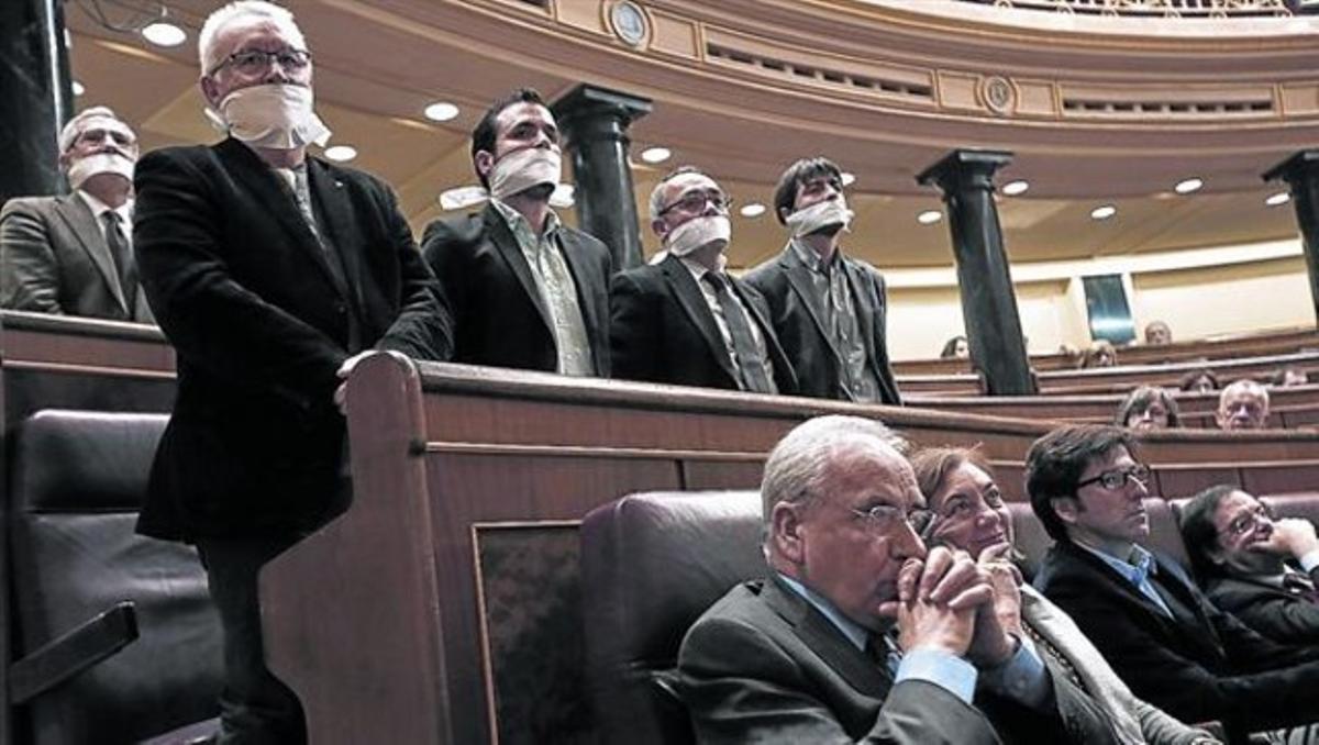 Diputados de Izquierda Plural, amordazados ayer durante el pleno del Congreso para protestar contra la ley de seguridad ciudadana.