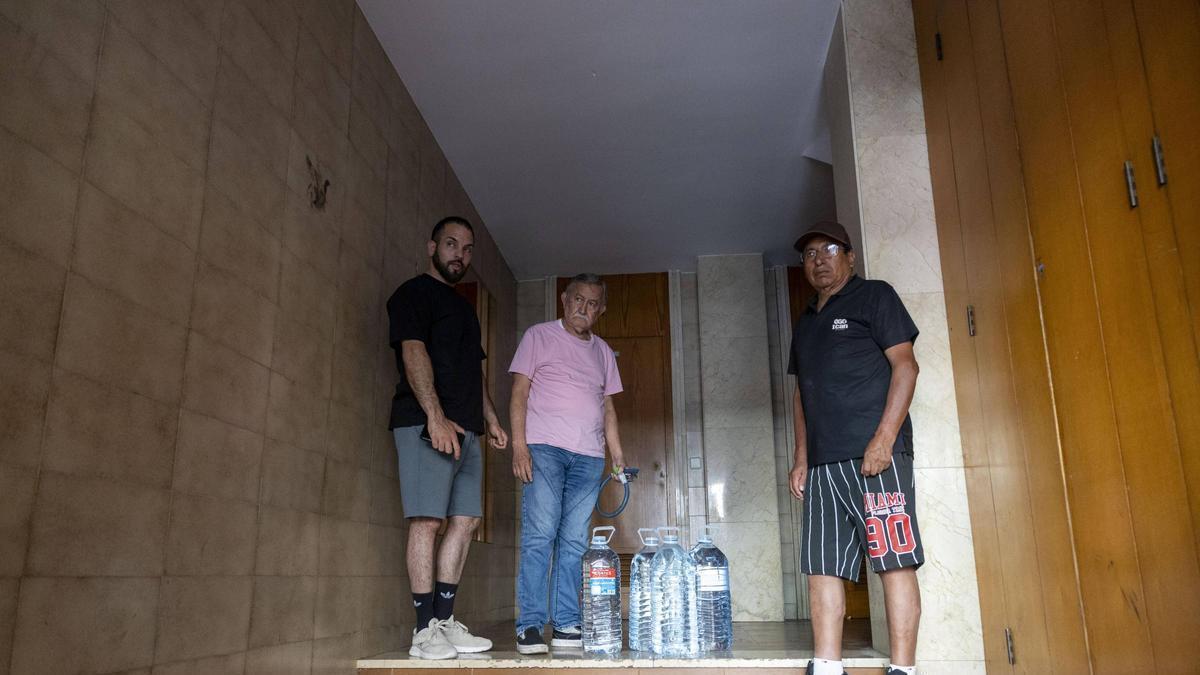 Damián, Osvaldo y Esteban, en el portal del edificio con garrafas.
