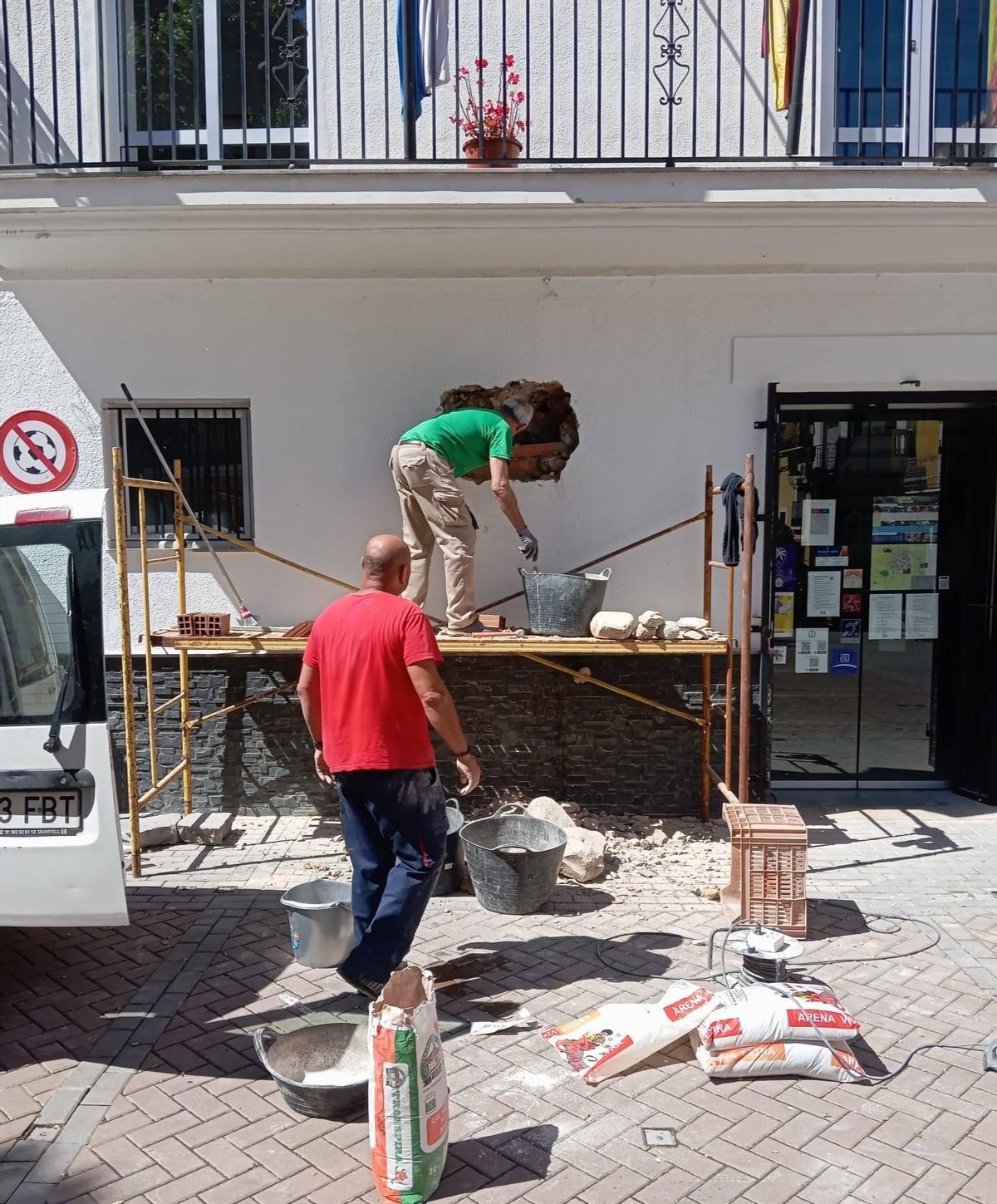 Operarios del ayuntamiento durante la colocación de la placa histórica en la fachada de la casa consistorial de Navajas.