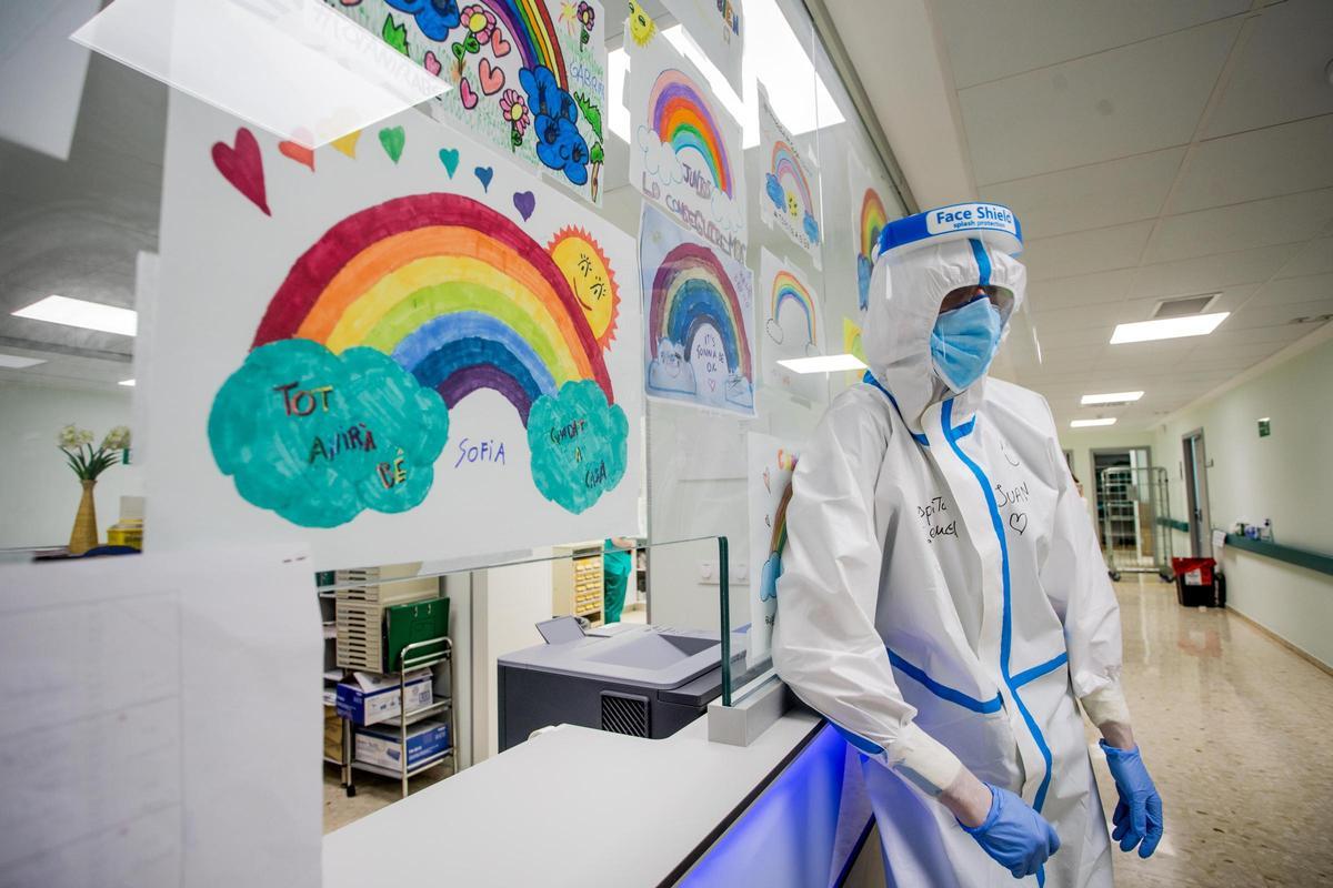 Un sanitario del Hospital General de València, en abril de 2020, junto a un dibujo de ánimo de una niña con el "Tot anirá bé".