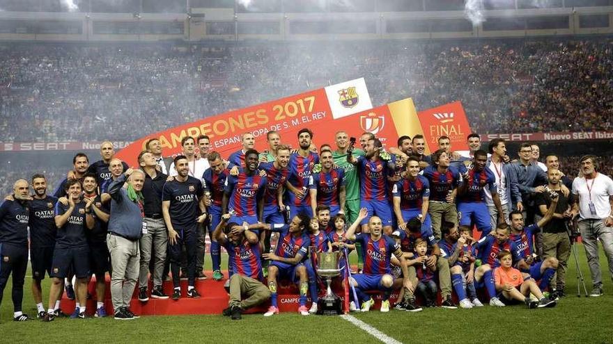 Los jugadores y técnicos del Barcelona posan con el trofeo sobre el césped del Vicente Calderón. // Efe