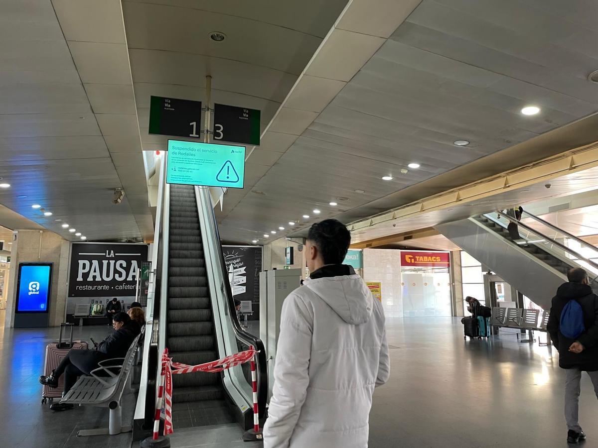 Un passatger mirant l'avís de la pantalla situada a la zona d'accés a les andanes de l'estació de Girona