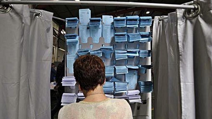 Una mujer, ante una cabina con papeletas.