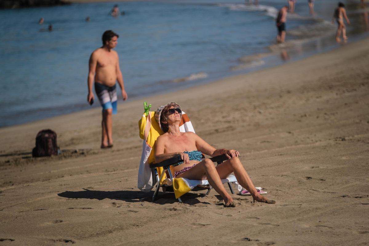 Una turista toma el sol sentada en su hamaca en una playa del sur de Tenerife.