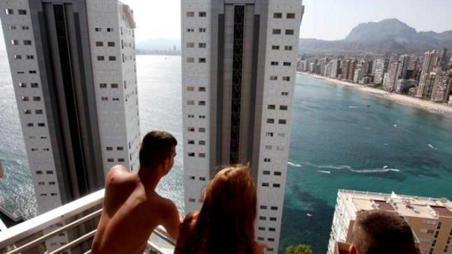 Una pareja observa la costa de Benidorm tras dos torres de apartamentos en Benidorm.