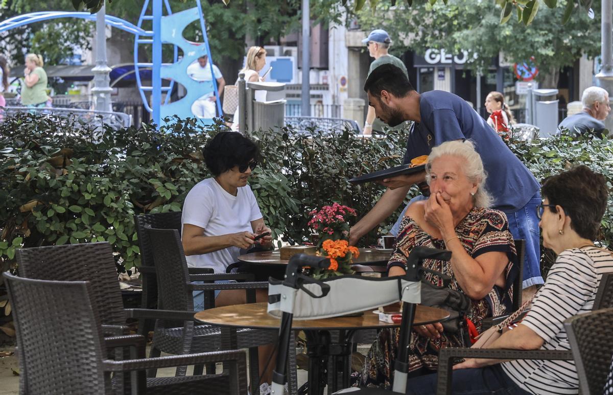 Un camarero atiende a los clientes de una terraza de Alicante.