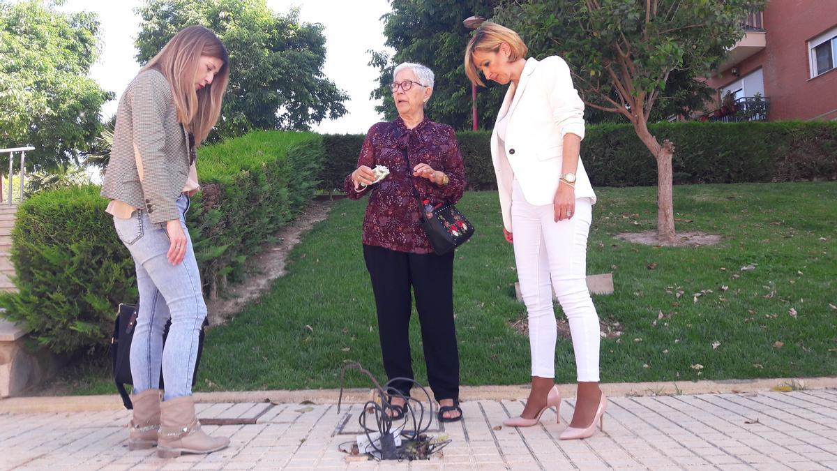 Rosa María Medina, Ángela Lafuente y María Belén Pérez contemplan los cables que han quedado en el suelo tras desaparecer una de las farolas.