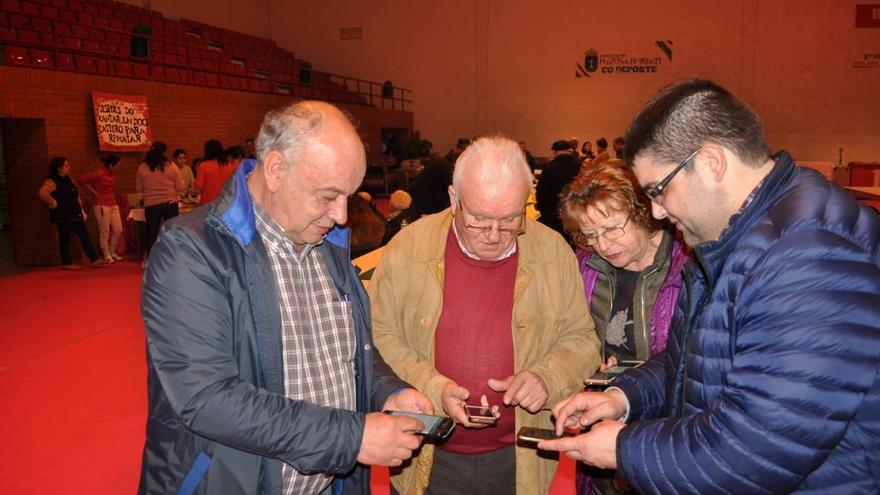 El alcalde de Pazos, Andrés Iglesias, y el edil Fran Amoedo, enseñan a unos vecinos a usar la aplicación. / FdV