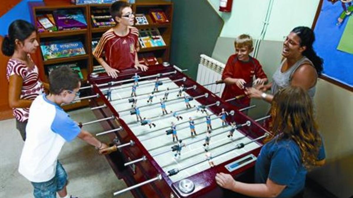 Unos niños juegan con su monitora en un local de la Fundació Catalana de l'Esplai en L'Hospitalet de Llobregat, ayer.