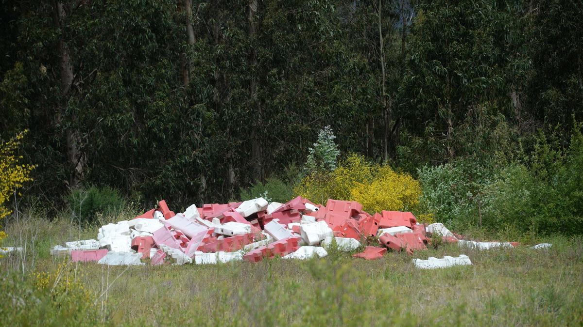Medianas de plástico precedentes de las obras del Eje Atlántico tiradas en un monte de Catoira.