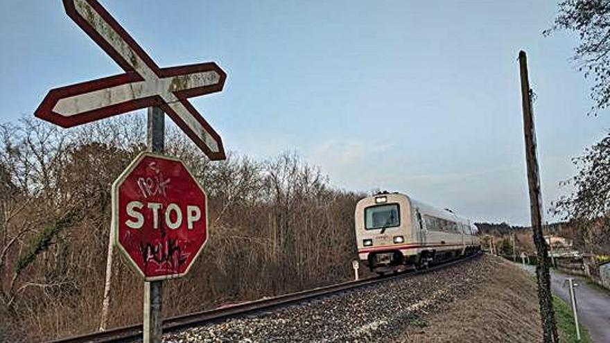 Un tren se aproxima a un paso a nivel en Cambre.