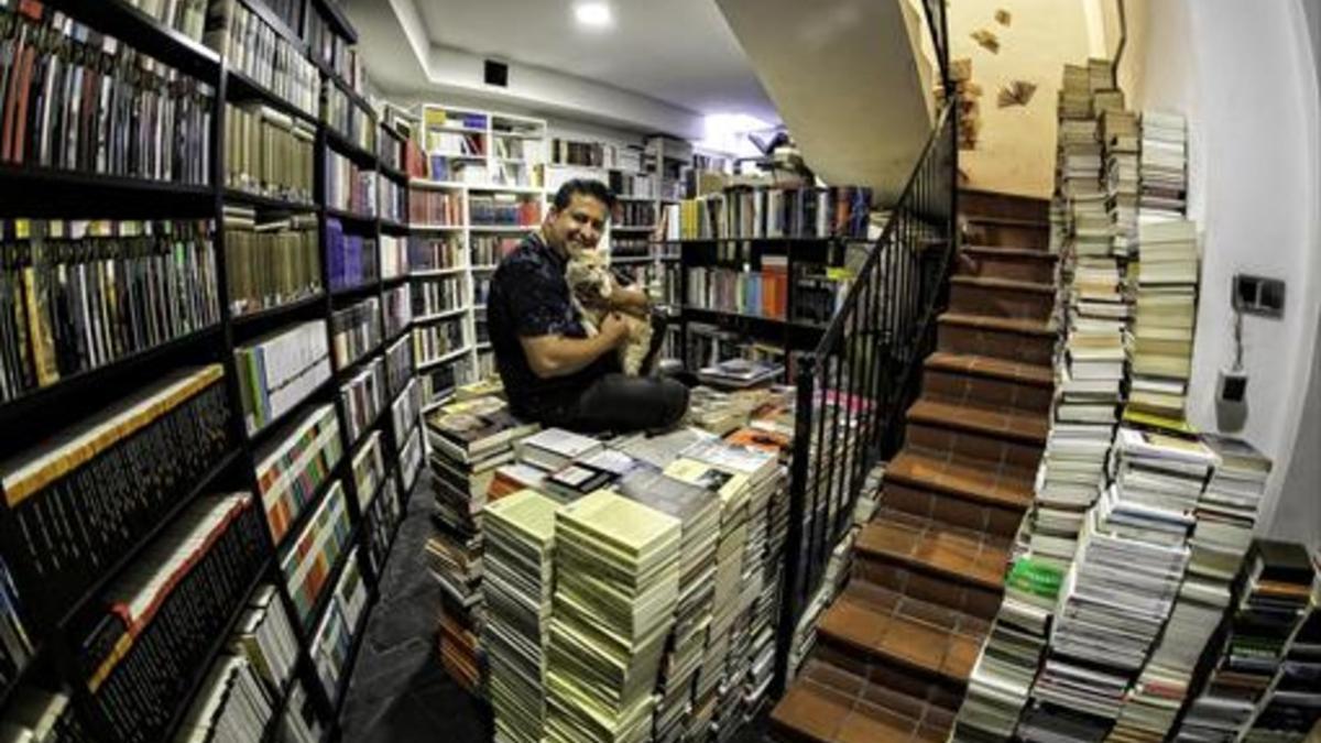 Ricard Ruiz Garzón en su biblioteca, sentado sobre libros de los que tiene que desprenderse, en Santa Coloma de Gramenet.