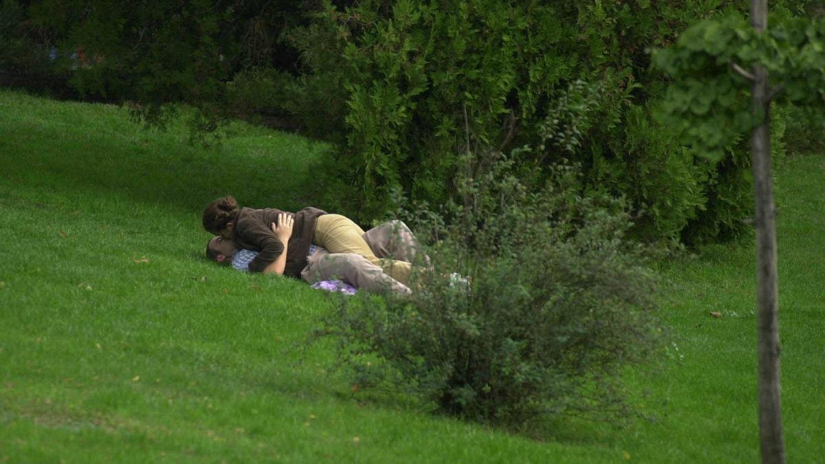 Una pareja se besa en un parque.