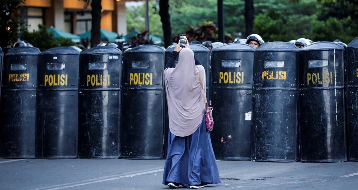 Una mujer fotografía a varios policías indonesios que trabajan en la protección de la sede de la Agencia de Supervisión Electoral en Yakarta (Indonesia), este viernes. Doscientas cincuenta y siete personas han sido detenidas en relación con los disturbios iniciados el martes en Yakarta tras anunciarse la reelección del presidente indonesio, Joko Widodo, que han dejado seis muertos y más de 200 heridos, informaron hoy las autoridades.