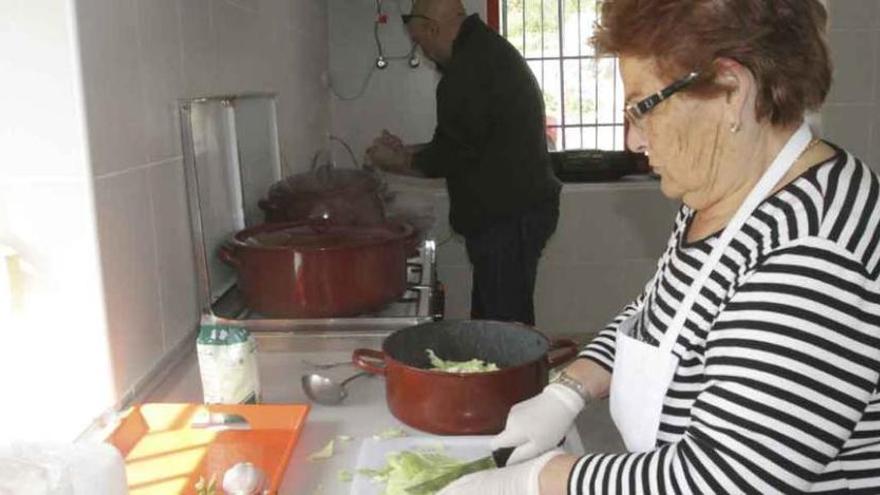 Arriba, dos voluntarios en la cocina, preparando la comida para los usuarios del centro de San José Obrero. A la izquierda, algunos de los participantes en la cena solidaria que se organizó la semana pasada en la capital para recaudar fondos para la iniciativa vecinal.