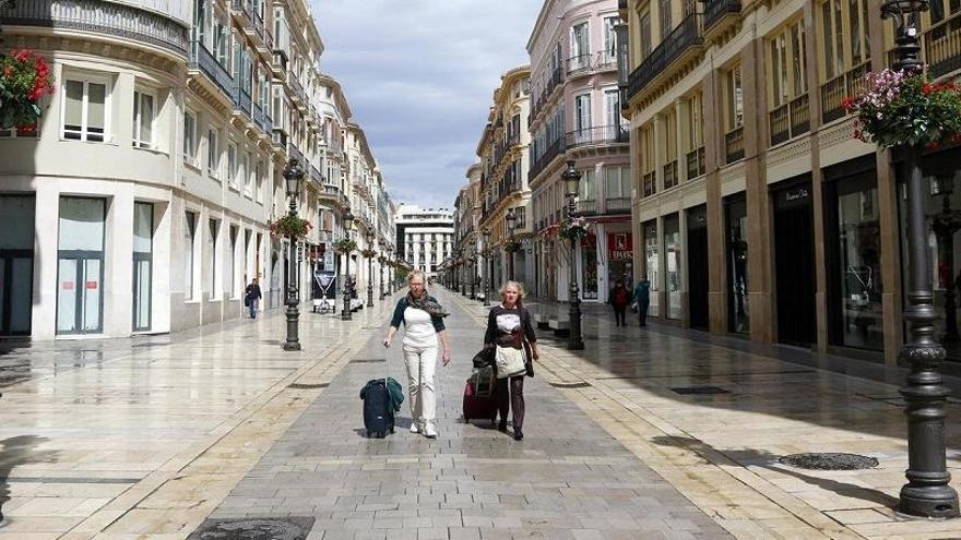 Dos personas con maletas recorren la calle Larios.