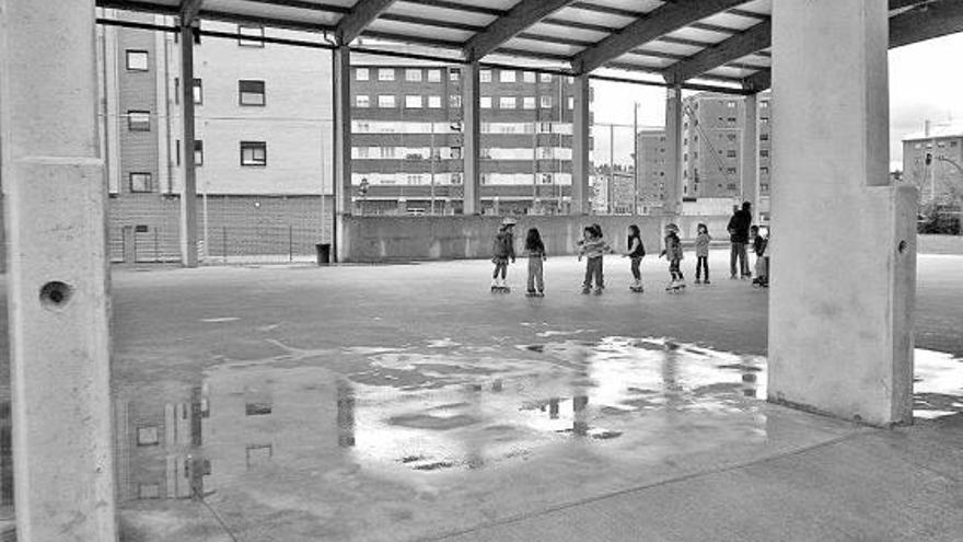 Un grupo de niños, en la cancha deportiva del Colegio Ángel González, llena de agua.