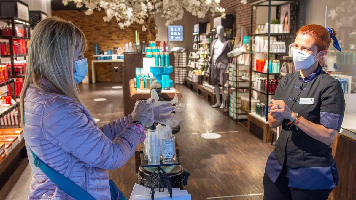 Una mujer con mascarilla se dispone a entrar en una tienda, en el Portal de l'Àngel de Barcelona