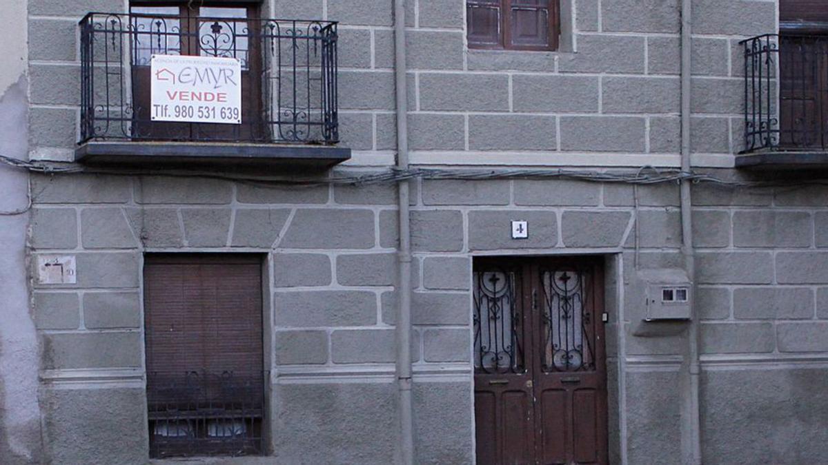 Una mujer pasa frente a una casa en venta. | LOZ