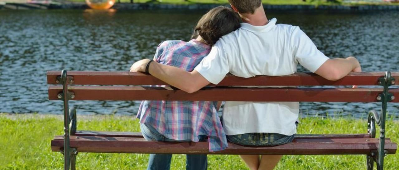 Una pareja de adolescentes, en el banco de un parque.
