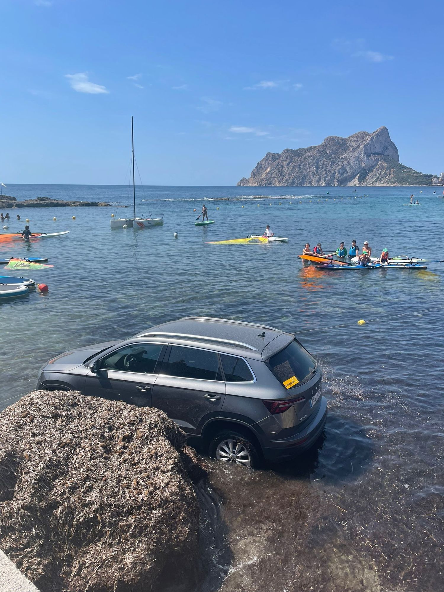 La imagen completa del coche sumergido en la playa de Les Bassetes, con el Peñón de Ifach al fondo