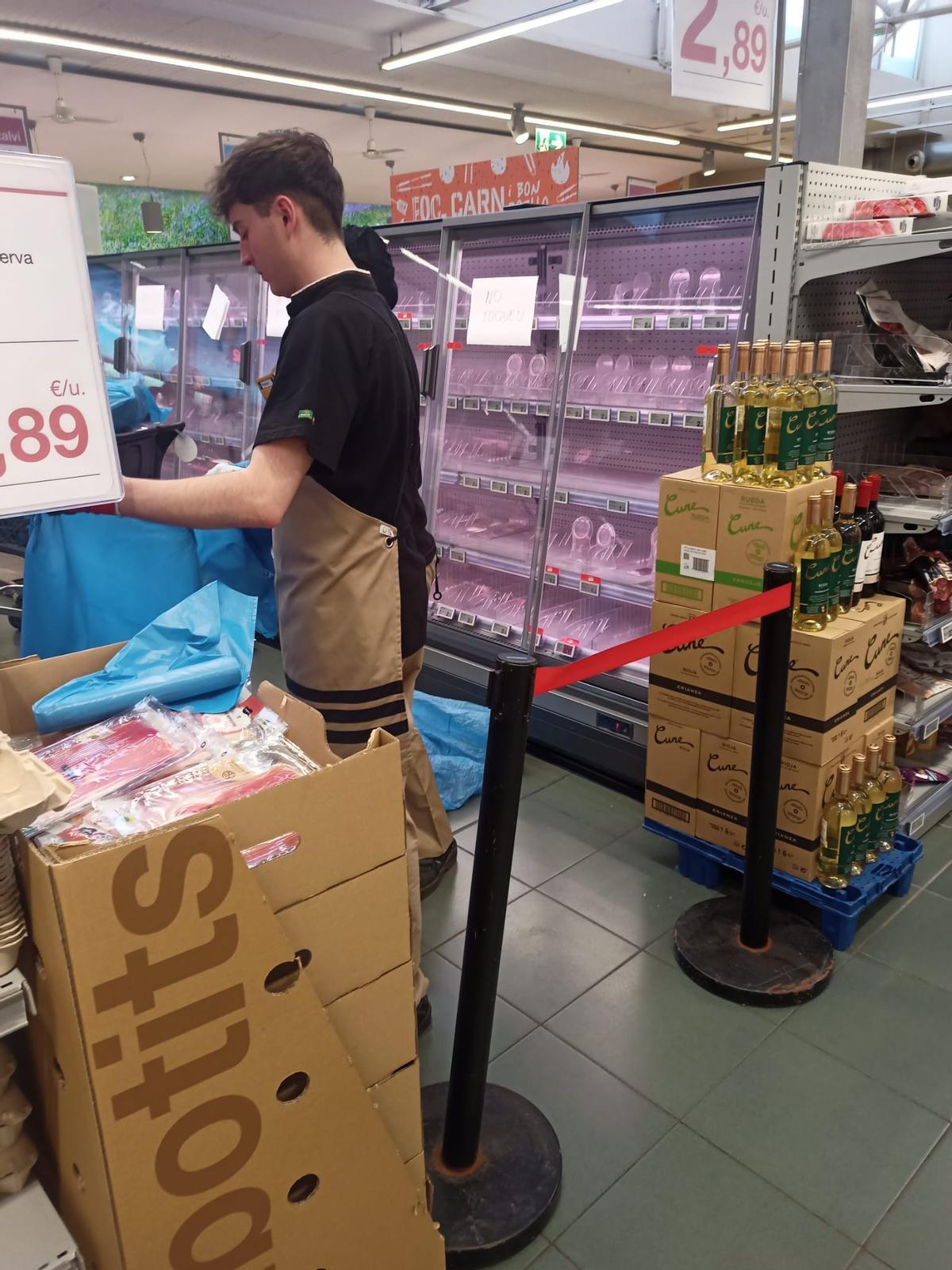 Un trabajador prepara una bolsa de basura para depositar alimentos afectados por el apagón en un supermercado de Barcelona.