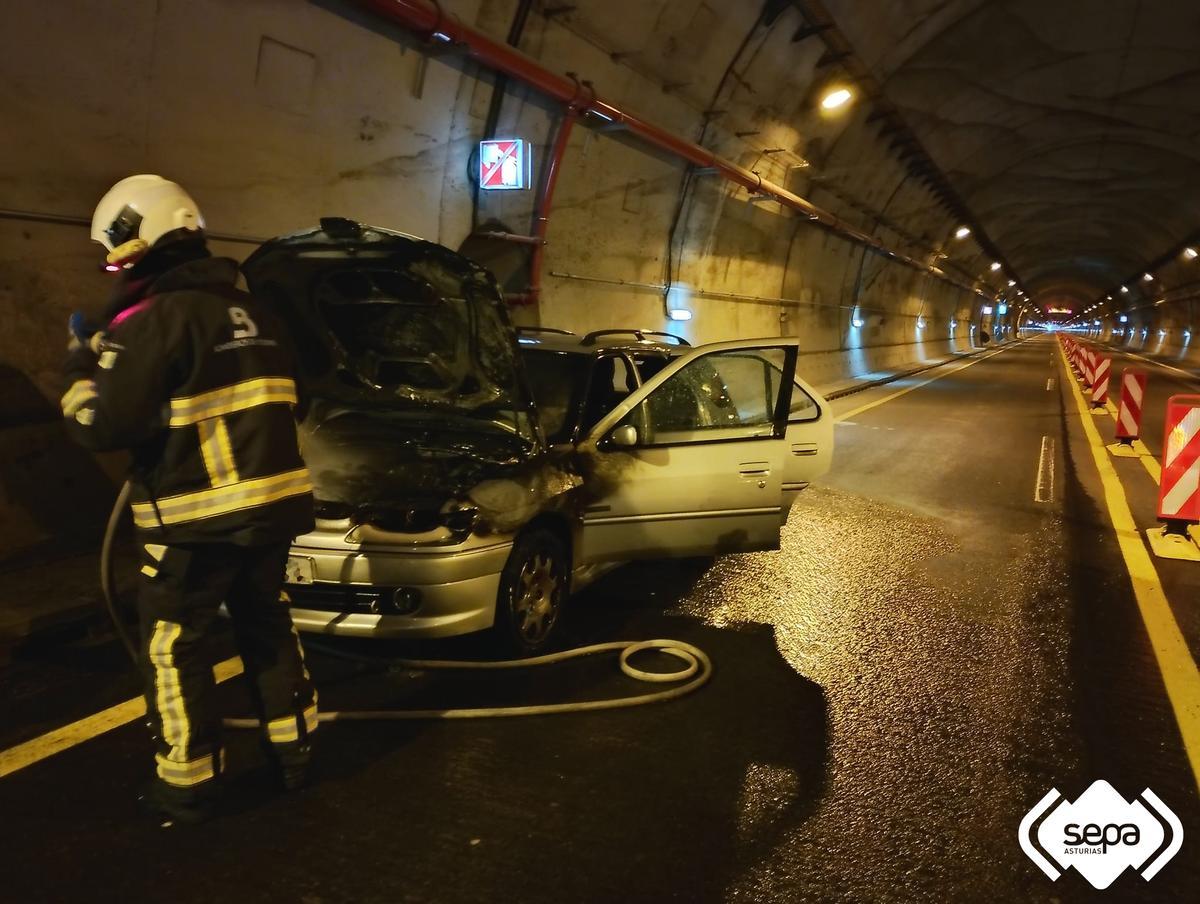 Un bombero junto al vehículo calcinado.
