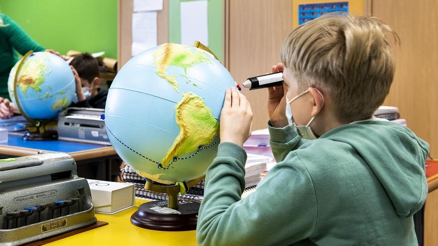 Un nen treballa amb una bola del món amb relleu en un centre educatiu