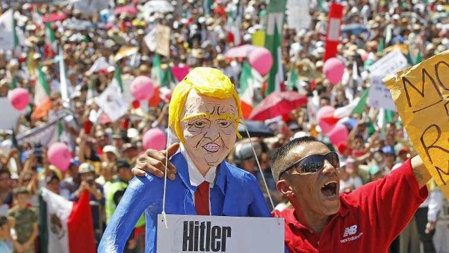 Un hombre exhibe un monigote de Trump, con un cartel sobre Hitler, en la protesta de Ciudad de México. // Efe