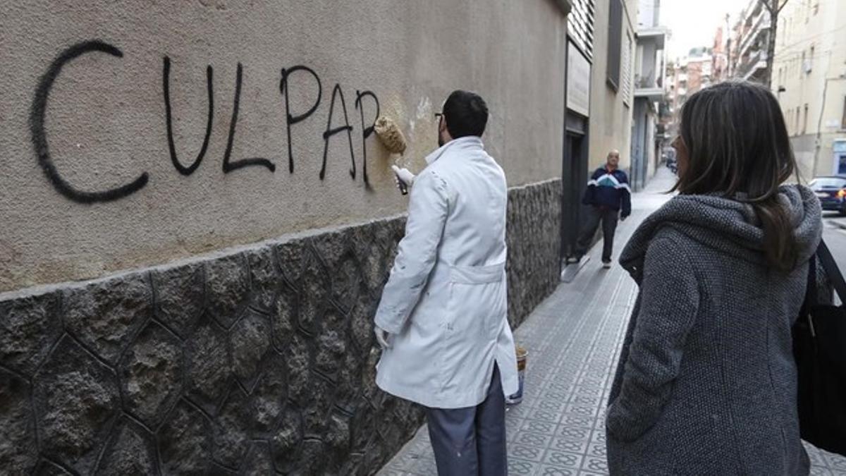 Un trabajador borra una pintada en el muro del colegio de los Maristas de Sants-Les Corts.