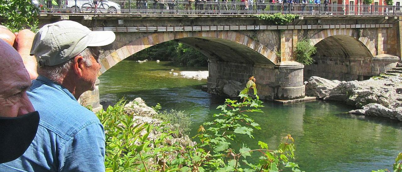 La gente en torno al coto El Puente Romano, observando la pesca.