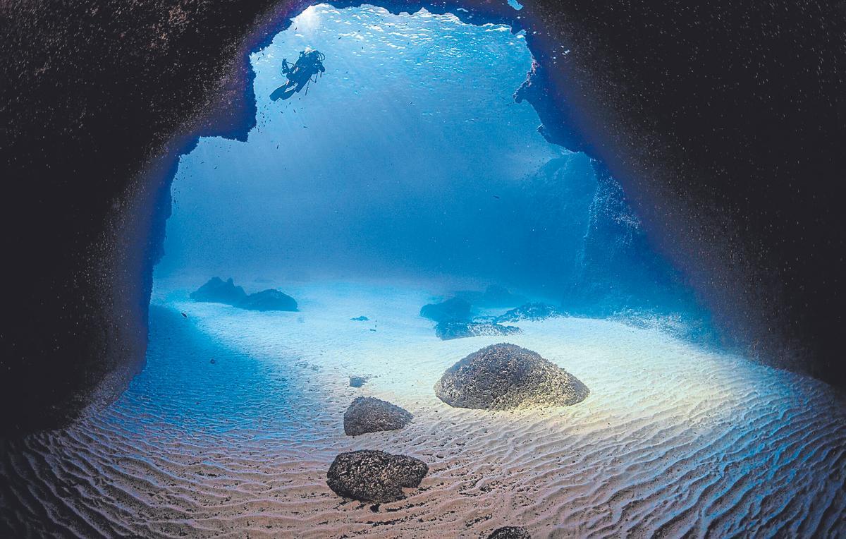 Un buceador se adentra en una de las cuevas de Migjorn en Formentera.