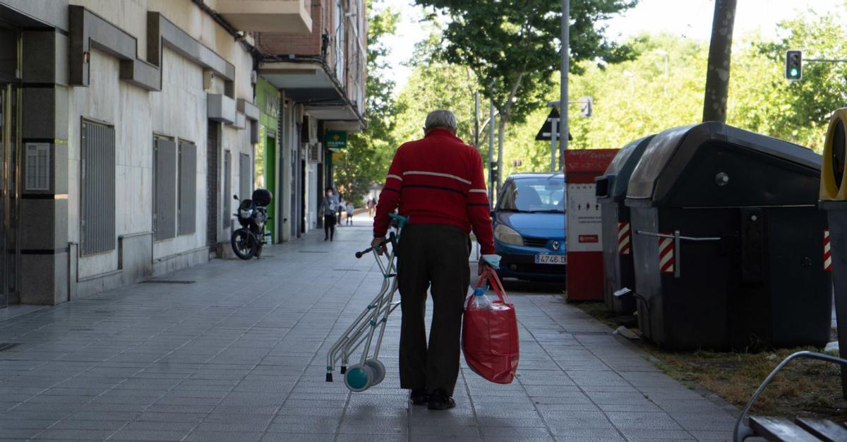 Un hombre camina por la acera, andador en mano. | Jose Luis Fernández