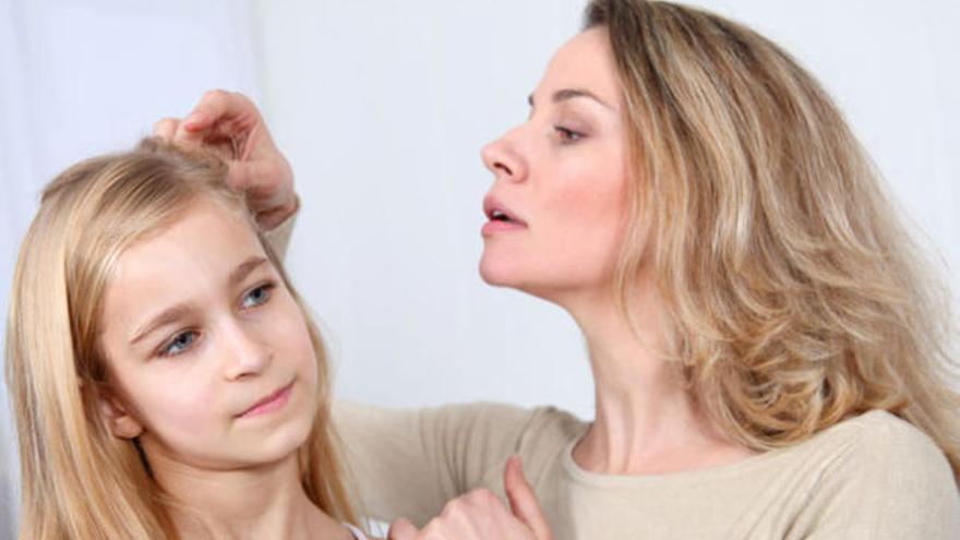 Una madre revisa el cabello de su hija