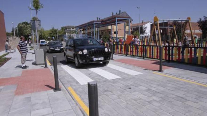 Varios vehículos circulan junto al nuevo parque infantil de la zona en la que se ha construido el aparcamiento subterráneo.