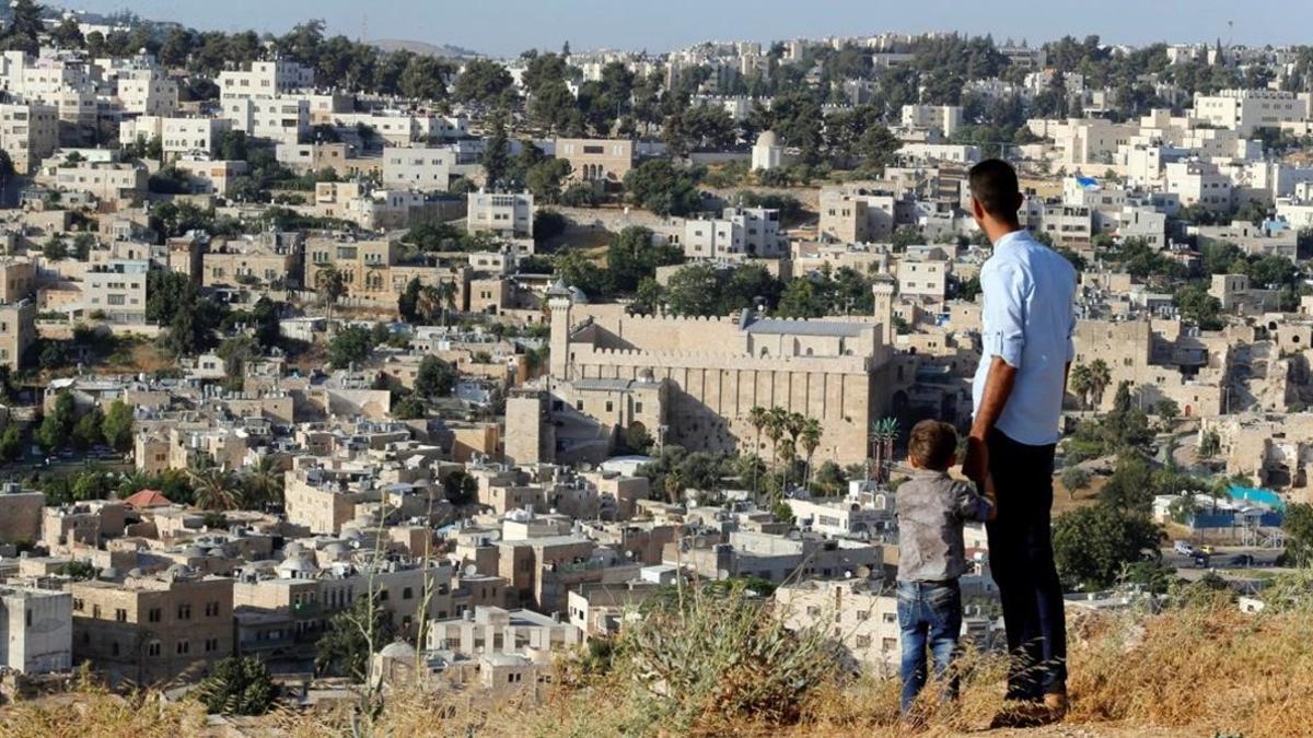 Unos palestinos miran la ciudad de Hebrón desde la montaña.