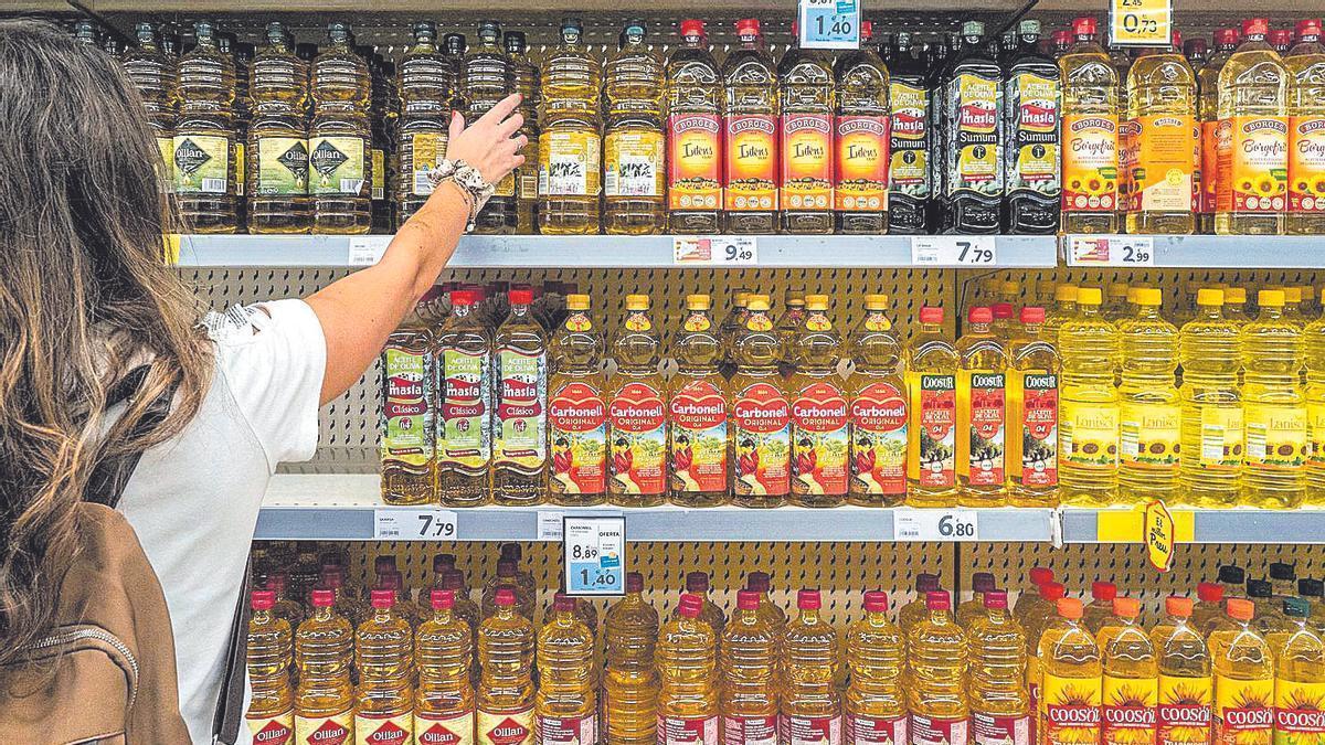 Una clienta d’un supermercat tria una ampolla d’oli d’oliva