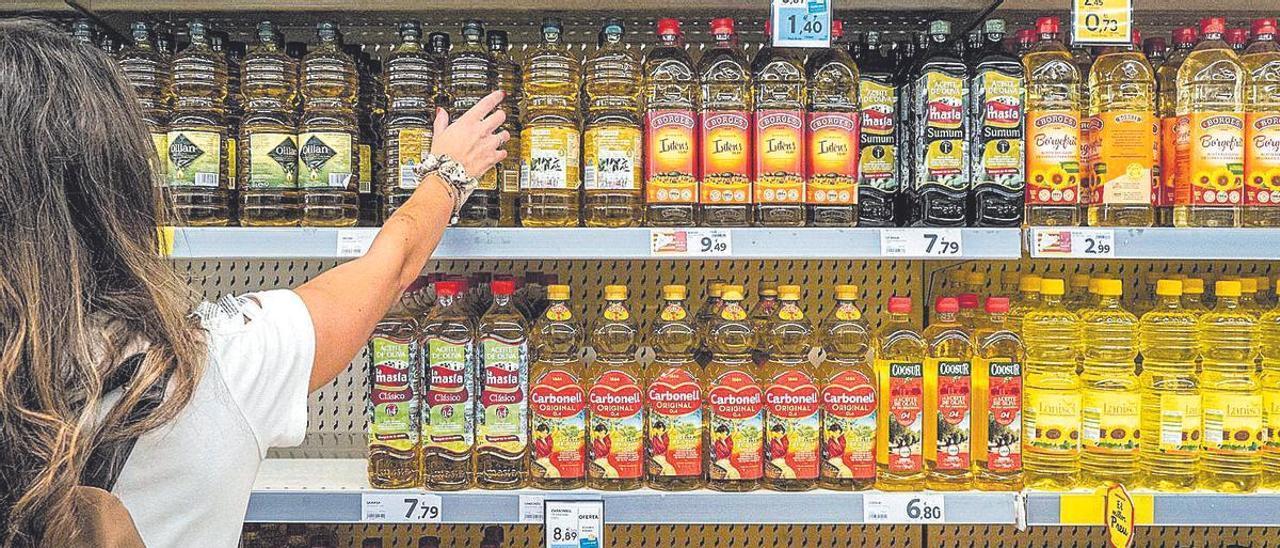 Una clienta d’un supermercat tria una ampolla d’oli d’oliva, que fa mesos que puja de preu