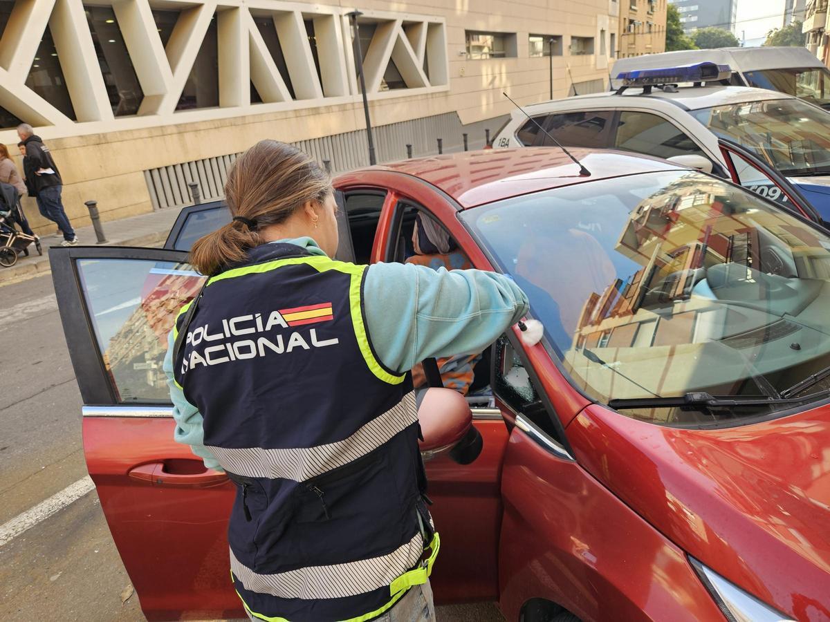 Una agente de la Policía Científica inspecciona un coche donde robaron esta semana tras romper una ventanilla.