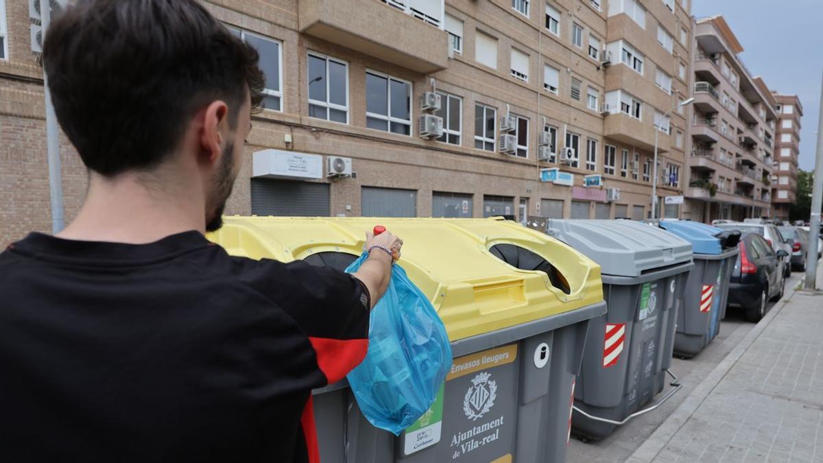 Un joven de Vila-real hace uso de los contenedores específicos para reciclar residuos domésticos.