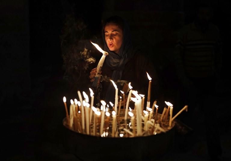 Una mujer cristiana apaga unas velas en el interior de la Iglesia del Santo Sepulcro en la antigua ciudad de Jerusalén. THOMAS COEX / AFP