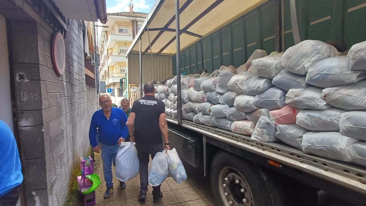 Varios vecinos ayudando a descargar un camión de ropa para enviar a la gente necesitada.